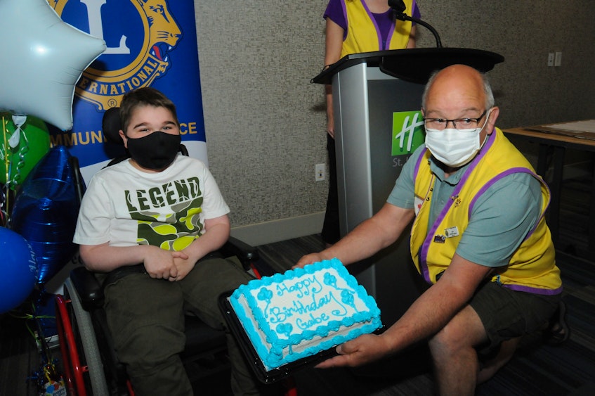 Even with his mask, it's not hard to know Gabe Tucker is smiling as he is presented with a birthday cake by Lions Club member Fred Thompson during Sunday's ceremony at the Holiday Inn Express in St. John’s. — Joe Gibbons/The Telegram