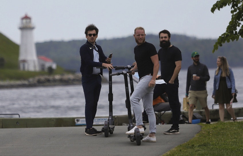 Young men prepare ride scooters on the waterfront in Halifax on Saturday, June 19, 2021. - Tim Krochak
