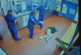 Halifax police constables Justin Murphy, Donna Lee Paris and Ryan Morris get ready to transport Corey Rogers from the booking area to a cell on the night of June 15, 2016, in this photo taken from a police video. Rogers, who had a spit hood over his head, later died in the cell from asphyxiation. The Nova Scotia Police Review Board is hearing an appeal launched by Rogers' mother, Jeannette, regarding the internal discipline handed out to the three arresting officers.