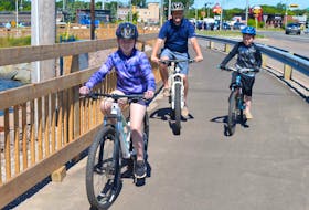 Mark Weeks, centre, goes for a bike ride on the Hillsborough Bridge active transportation path with his two children, Addison, left, 11, and Carter, 8, on June 24 in Charlottetown.