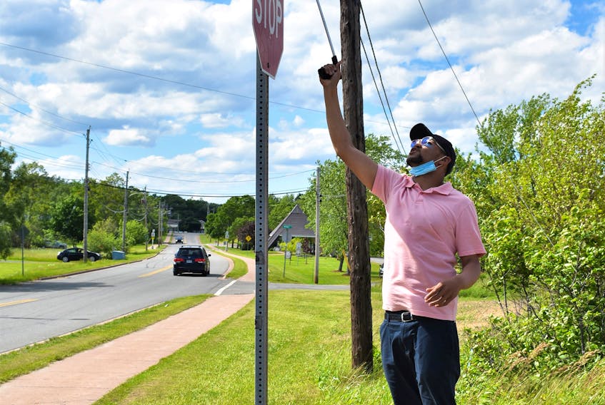 Wayne Desmond, who started the initiative, attempts to remove the cloth which was hiding the street sign’s new name – Reddick Lane. The reacher didn’t work, but assistance by a couple of family members quickly did.