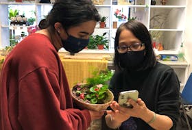 Co-owner of David's Garden and Flower shop Evain Chan (right) translates instructions on how to take care of the plant this customer has just bought. 