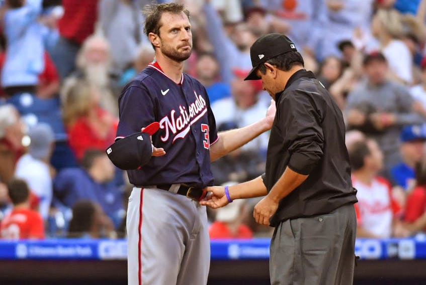 Max Scherzer of the Washington Nationals, left, allows the umpire to check his hat and belt for foreign substances. Scherzer was checked three times in four innings for substances and nothing was found. USA TODAY