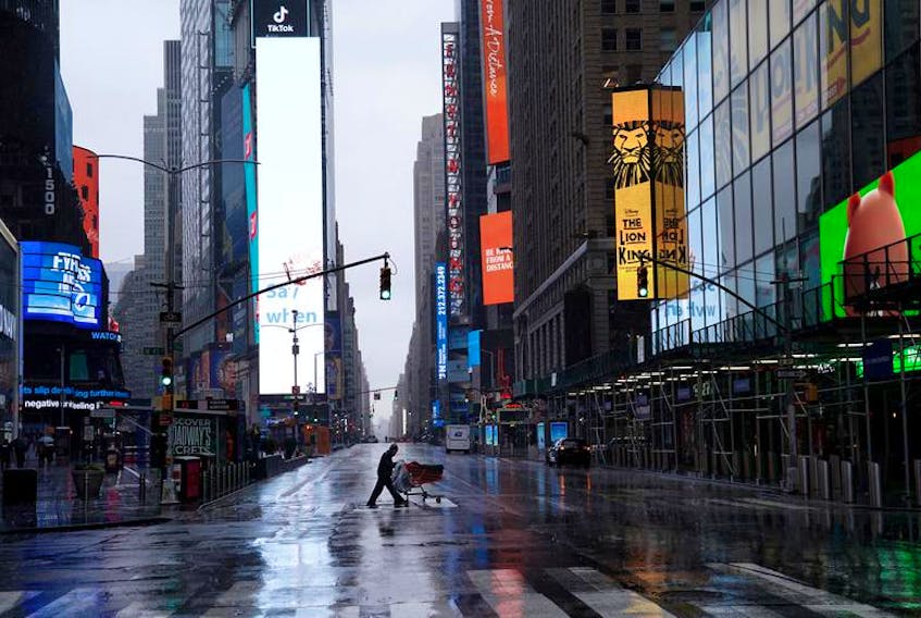 A homeless person pushes his belongings through a deserted Times Square in Manhattan, March 23, 2020.
