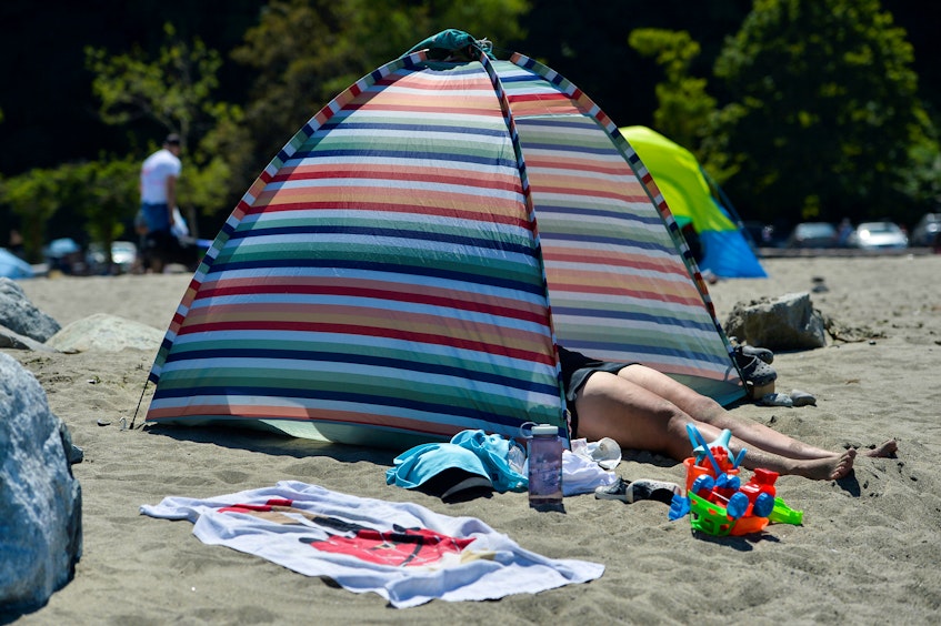 A beach-goer makes shade with a tent during the scorching weather of a heat wave in Vancouver on Sunday, June 27, 2021. - Jennifer  Gauthier/Reuters