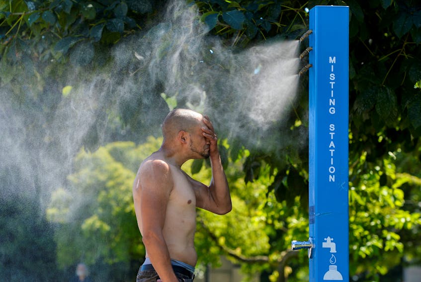 A man cools off at a misting station during the scorching weather of a heat wave in Vancouver on Sunday, June 27, 2021.