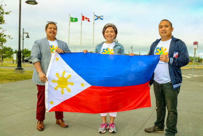 From left, Julius Garcio, Elena Hernandez Young and Jon Morales hold up the flag of the Philippines to celebrate Filipino Heritage Month. JESSICA SMITH/CAPE BRETON POST