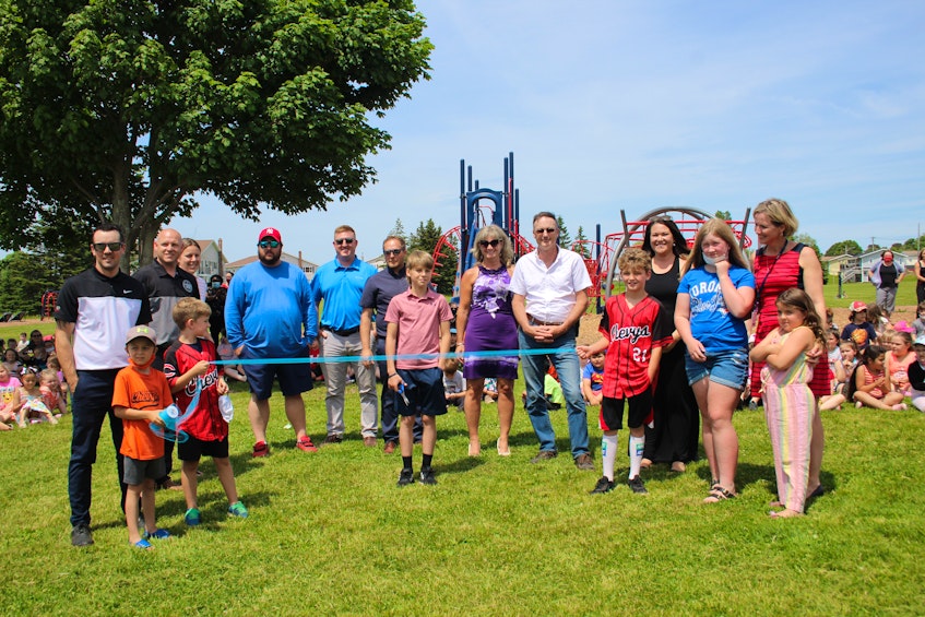 Members of the playground committee, students and sponsors of the equipment gather for the ribbon cutting to celebrate the official opening. - Kristin Gardiner