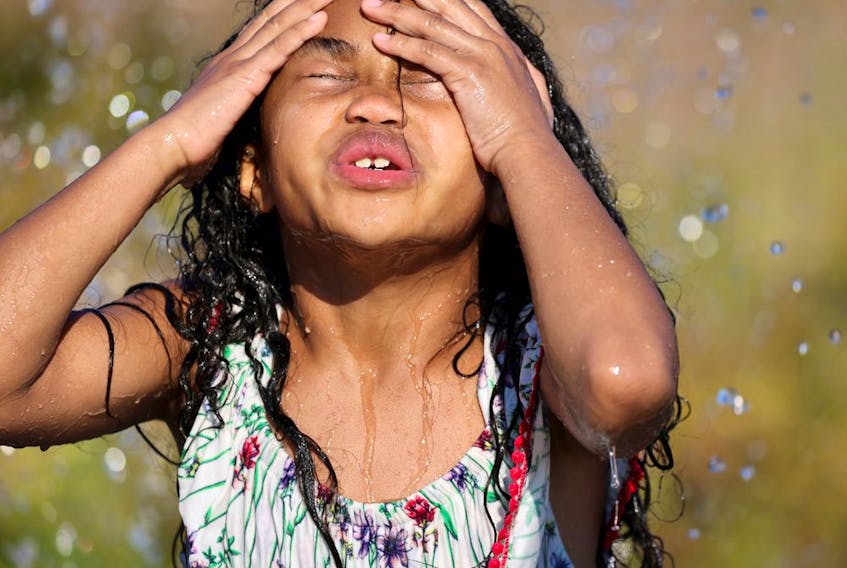 A child plays in water at a park during a heatwave.