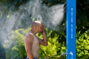  A man cools off at a misting station during the scorching weather of a heatwave in Vancouver on Sunday.