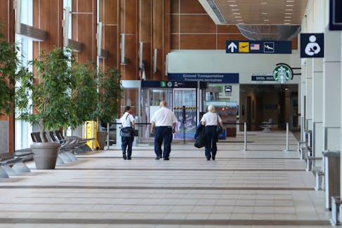 Canadian Air Transport Security Authority (CATSA) employees walk down an eerily quiet hallway toward arrivals at Halifax Stanfield International Airport Tuesday afternoon. With Phase 3 of the lifting of COVID-19 restrictions the airport might be busier.