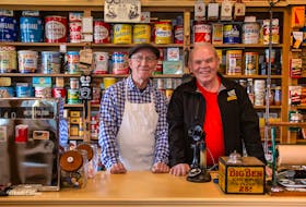 Ed Coleman is pictured with Rawdon’s general store/museum proprietor Marvin McPhee.  On the shelves behind them are examples of the kind of tins MacPhee first started to collect. - Michelle Coleman 