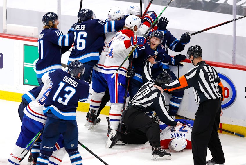 Winnipeg Jets forward Nikolaj Ehlers (27) attempts to keep players away from injured Montreal Canadiens centre Jake Evans (71) after a hit by Jets centre Mark Scheifele late in Game 1 of the second round of the 2021 Stanley Cup Playoffs at Bell MTS Place in Winnipeg on Wednesday.