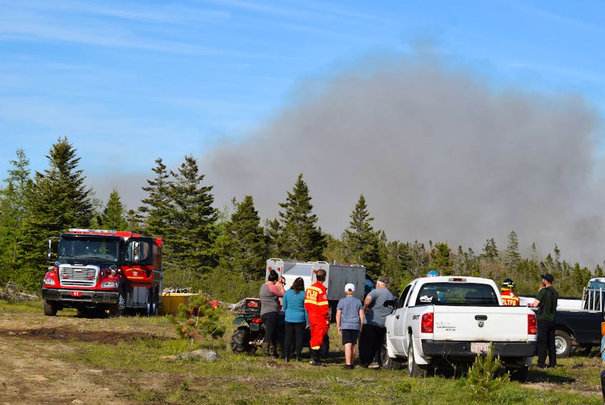 Smoke billows up from the backwoods in Villagedale  as volunteer firefighters and others watch and tend to the water supply to fight the fire on June 2. KATHY JOHNSON  
