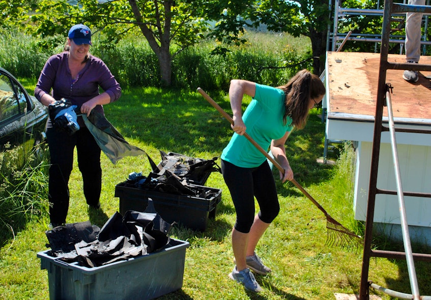 Sisters Stacey (left) and Melanie Swim were among the volunteers who helped the work party that replaced the roof on Susan Kenney’s home in Clark’s Harbour on June 24. KATHY JOHNSON - Kathy Johnson