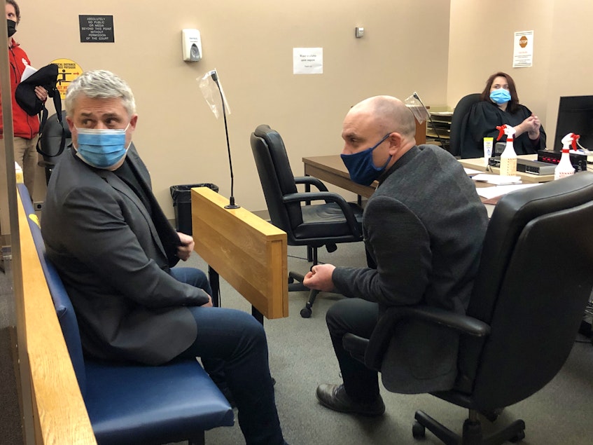 Kurt Churchill (left, in blue mask) sits in Provincial Court in St. John's with his lawyer, Robby Ash. Last year, Churchill was found guilty of threatening a police officer. — File Photo