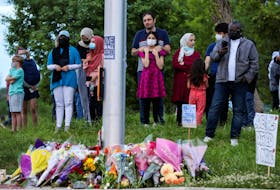 People gather at a makeshift memorial at the fatal crime scene where a man driving a pickup truck jumped the curb and ran over a Muslim family in what police say was a deliberately targeted anti-Islamic hate crime, in London, Ont., June 7, 2021.
