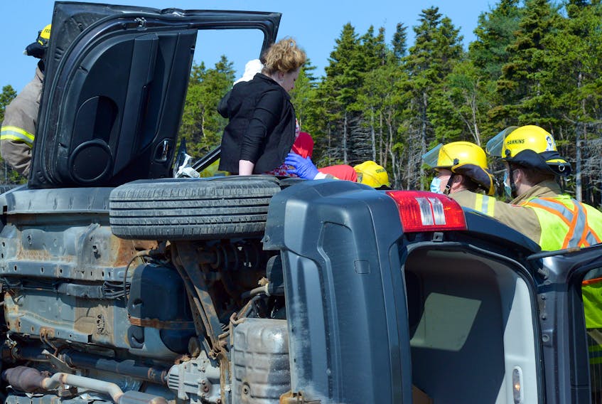 Firefighters help a woman from her overturned Jeep but she suffered only minor injuries in a single-vehicle rollover on Pitts Memorial Drive Tuesday morning. Keith Gosse/The Telegram