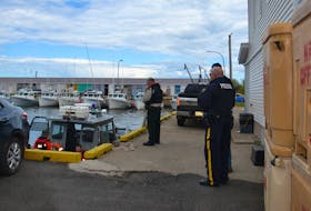 Police officers are shown at the wharf in Beach Point following a fatal fishing boat collision in 2018 that killed Chris Melanson and Justin MacKay.