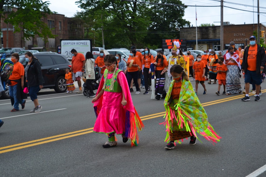 Jaylee Spence, 9, and Alivia MacLean, 6, walk to the beat of nearby drummers as the procession moved along George Street from the northend of Sydney to Wentworth Park. ARDELLE REYNOLDS/CAPE BRETON POST