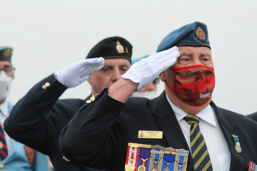 Nathan Lehr (right), president of the Royal Canadian Legion, Newfoundland and Labrador Command, and Greg Grenning, past president of the RCL Branch 1, salute as the bugler plays. — Joe Gibbons/The Telegram