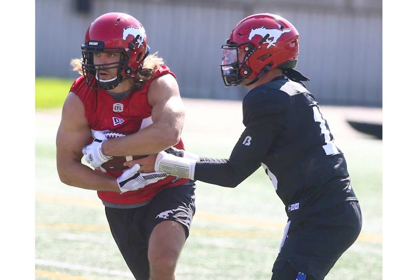  Calgary Stampeders running back Ante Milanovic-Litre takes a handoff from quarterback Bo Levi Mitchell during the CFL team’s first training camp practice in Calgary on Saturday, July 10, 2021.