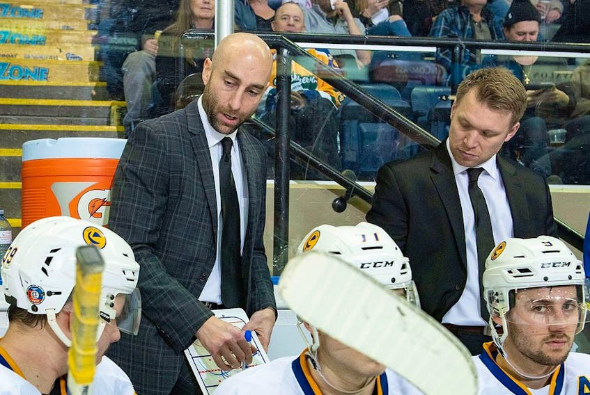KELOWNA, BC - DECEMBER 01: Saskatoon Blades' head coach Mitch Love and assistant coach Ryan Keller stand on the bench and discusses a play against the Kelowna Rockets at Prospera Place on December 1, 2018 in Kelowna, Canada.