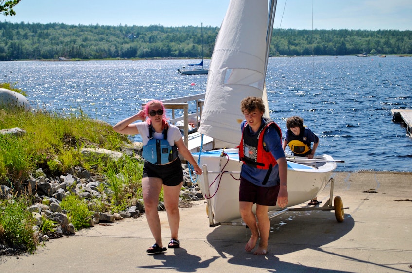 Shelburne Harbour Yacht Club Sailing Academy instructors Lia Oickle (from left), Aaron Hobbs and Rafael Pedro bring an Opti sailing dinghy  up the slipway at the Shelburne waterfront marina after a day on the water. KATHY JOHNSON - Kathy Johnson