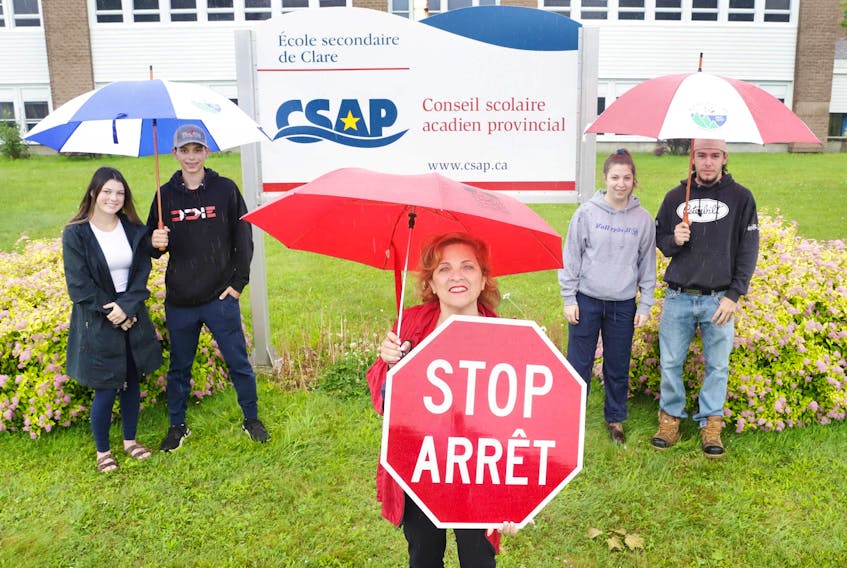 Lena Metlege Diab, Minister of Acadian Affairs and Francophonie, holds a bilingual stop sign alongside students from École Secondaire de Clare (l-r): Blake Theriault, Crystal Madden, Nicole Thibodeau and Gaetan Deveau. 
Communications Nova Scotia photo