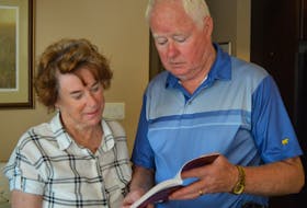 Ernie MacAulay, right, and his wife, Ruthann, look through his first book, a non-fiction story about the 1951 murder of his aunt, Mary Ann MacKinnon.