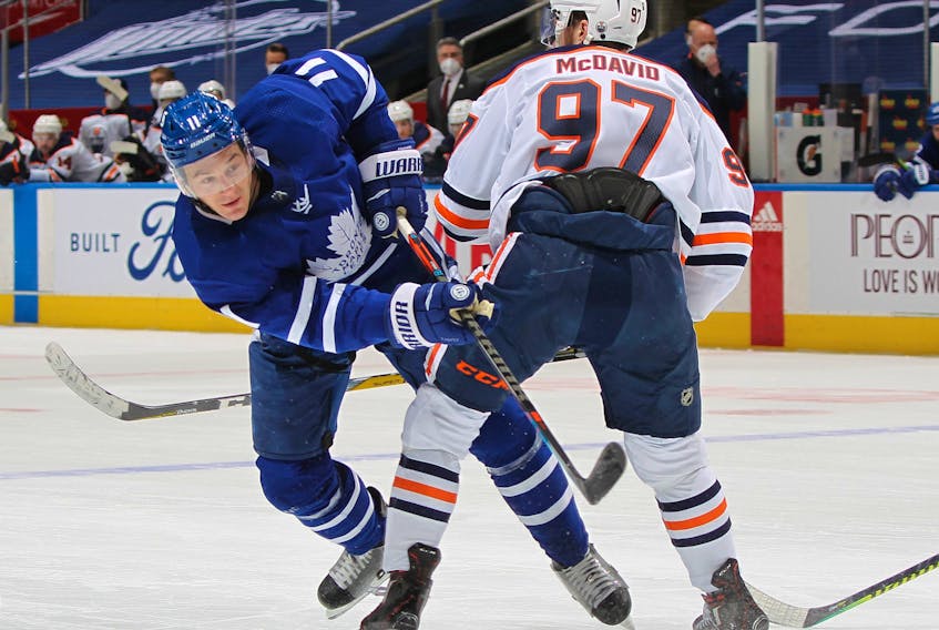 Connor McDavid (97) of the Edmonton Oilers holds up Zach Hyman (11) of the Toronto Maple Leafs at Scotiabank Arena on March 29, 2021, in Toronto.