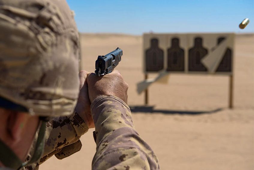 The Canadian military's plan to replace its 1940s-era Browning handguns, shown in this 2015 photo being used by Canadian troops in the Middle East, has been paused after a complaint from a firm representing a major gun manufacturer.