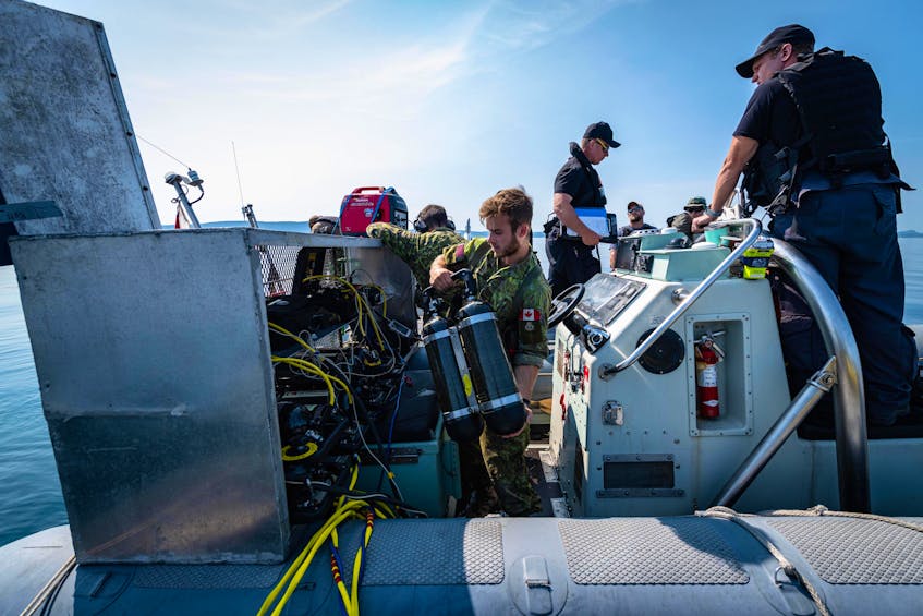 A crew monitors the progress of divers recovering ordnance from the vessel below. - Contributed