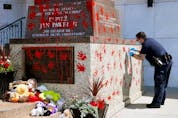  An Edmonton police constable collects evidence on June 27, 2021 after a statue of Pope John Paul II outside the Holy Rosary Church in Edmonton was vandalized.