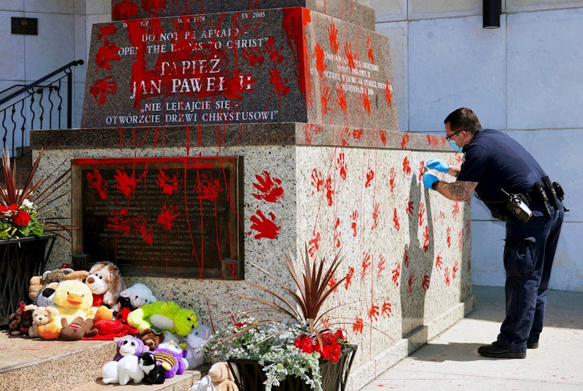  An Edmonton police constable collects evidence on June 27, 2021 after a statue of Pope John Paul II outside the Holy Rosary Church in Edmonton was vandalized.