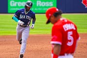 Shed Long Jr. of the Seattle Mariners runs the bases after hitting a two-run home run during the third inning as Santiago Espinal of the Blue Jays looks down at Sahlen Field on July 1, 2021 in Buffalo. 