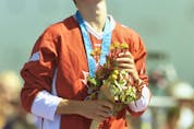  Simon Whitfield of Kingston, Ont., raises his head to the heavens as he stands on the podium with his gold medal and a bouquet of flowers in Sydney 2000 after winning the triathlon event.