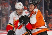 Robert Hagg (right) of the Philadelphia Flyers moves Michael Frolik of the Calgary Flames into the boards behind the net during the first period at the Wells Fargo Center on November 23, 2019 in Philadelphia, Pennsylvania.