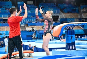 Halifax gymnast high-fives with coach David Kikuchi during team competition on Sunday at the Tokyo Olympics. - John Cheng/GymCan