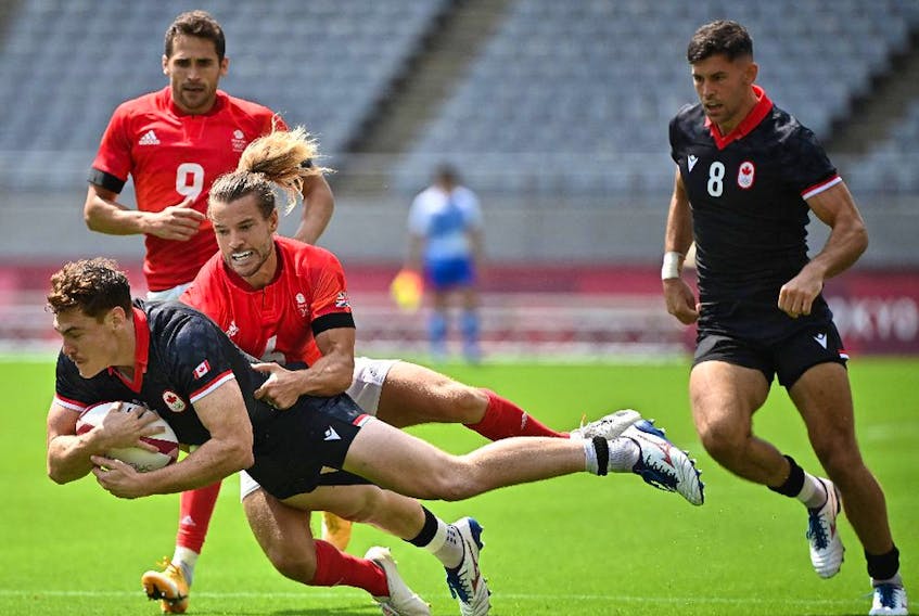 Canada's Phil Berna (L) is tackled by Britain's Tom Mitchell (C) in the men's pool B rugby sevens match between Britain and Canada during the Tokyo 2020 Olympic Games at the Tokyo Stadium in Tokyo on July 26, 2021. (Photo by Ben STANSALL / AFP)