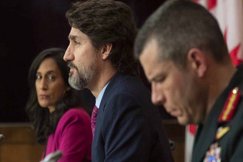 Public Services and Procurement Minister Anita Anand, left, and Maj.-Gen. Dany Fortin, right, look on as Prime Minister Justin Trudeau responds to a question during a news conference in Ottawa on Dec. 7, 2020.