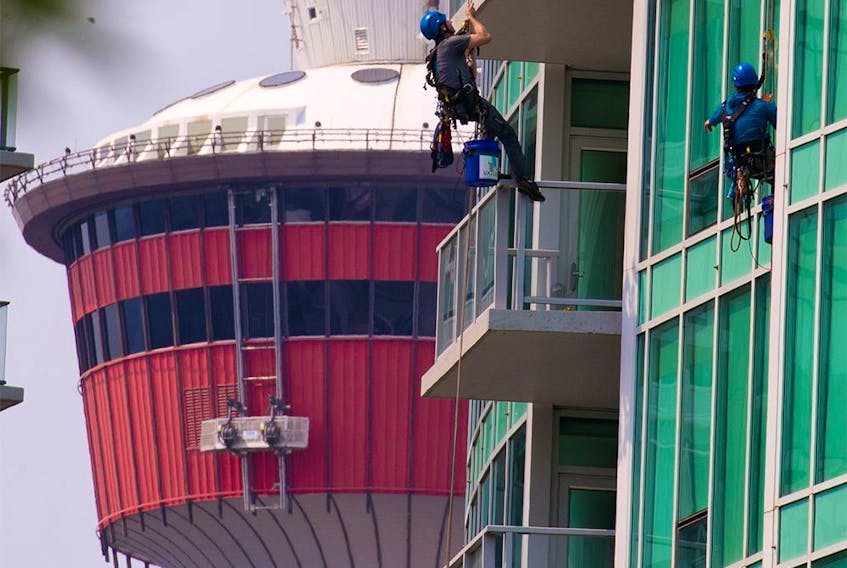 Window washers clean the glass on the Arriva tower in Calgary’s Victoria Park area on Monday, July 26, 2021. 