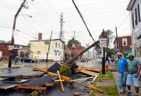 Passersby look at the debris on Agricola Street in September 2003 after hurricane Juan uprooted trees and downed power lines throughout the region.