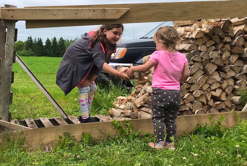 Chermaine Regular's children, Lilah, left, and Allie-Mae, work on their firewood business with help from their brother, Bentley. The children recently had firewood stolen from the end of their driveway.  