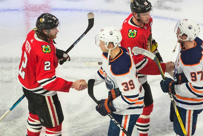Edmonton Oilers' Alex Chiasson (39) and Connor McDavid (97) shake hands with Chicago Blackhawks' Duncan Keith (2) and Jonathan Toews (19) following the NHL qualifying round in Edmonton on August 7, 2020.