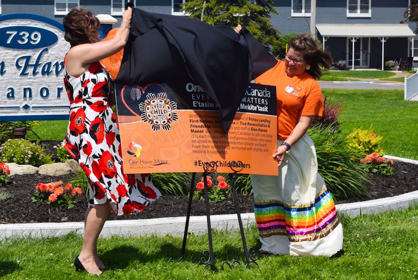 Glen Haven Manor CEO Lisa Smith, left, and Pictou Landing First Nation Chief Andrea Paul unveil a poster for a new campaign to raise money to help find and bring children who died in residential schools home.