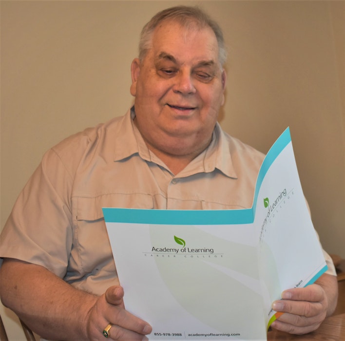 Barry Hill looks over the Academy of Learning folder of information on their business administration program which he can now successfully file away as a graduate. - Richard MacKenzie