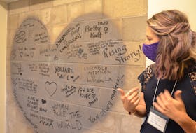 Chrysalis House executive director Ginger McPhee looks at the messages of hope and inspiration that staff members wrote on the outside of an elevator shaft in the new shelter to greet clients who arrive there. KIRK STARRATT
