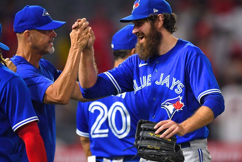 Blue Jays closer Jordan Romano celebrates with pitching coach Pete Walker after beating the Angles on Tuesday night. 