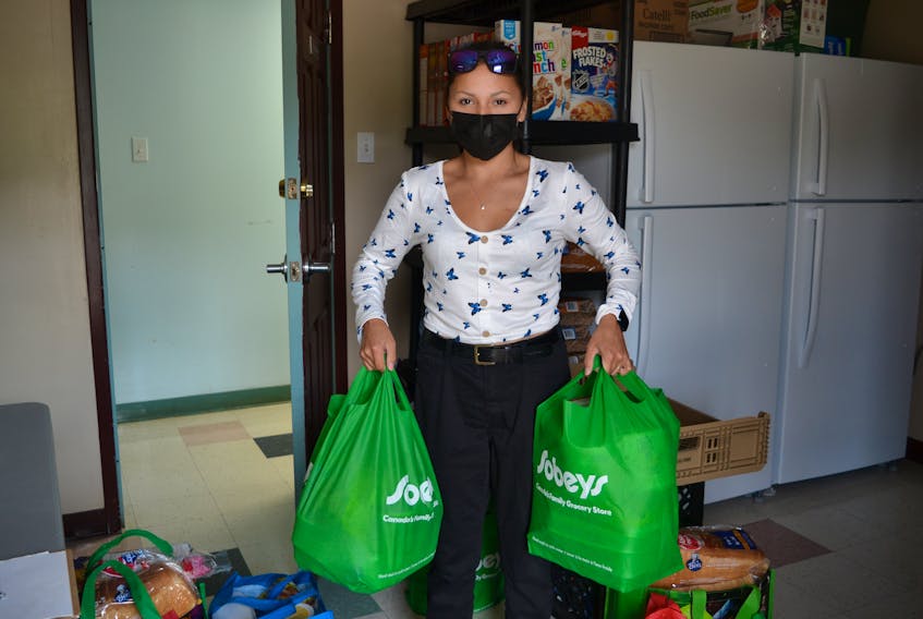 Volunteer Serena Young, who works at the We'koqma'q band office, holds food bags ready to go out the door at the new food bank in We'koqma'q First Nation, which fills phone orders from 20 to 30 families every two weeks. The food bank opened on June 1. ARDELLE REYNOLDS/CAPE BRETON POST